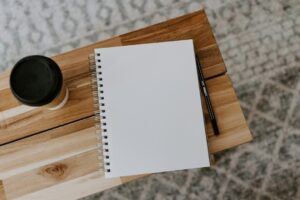 Offenes blankes Notizbuch mit Stift und Kaffee auf einem Holztisch